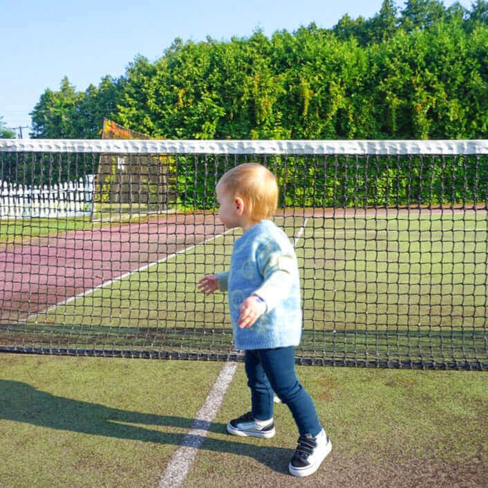 toddler walking on tennis court wearing smile jacquard sweater and navy rib leggings