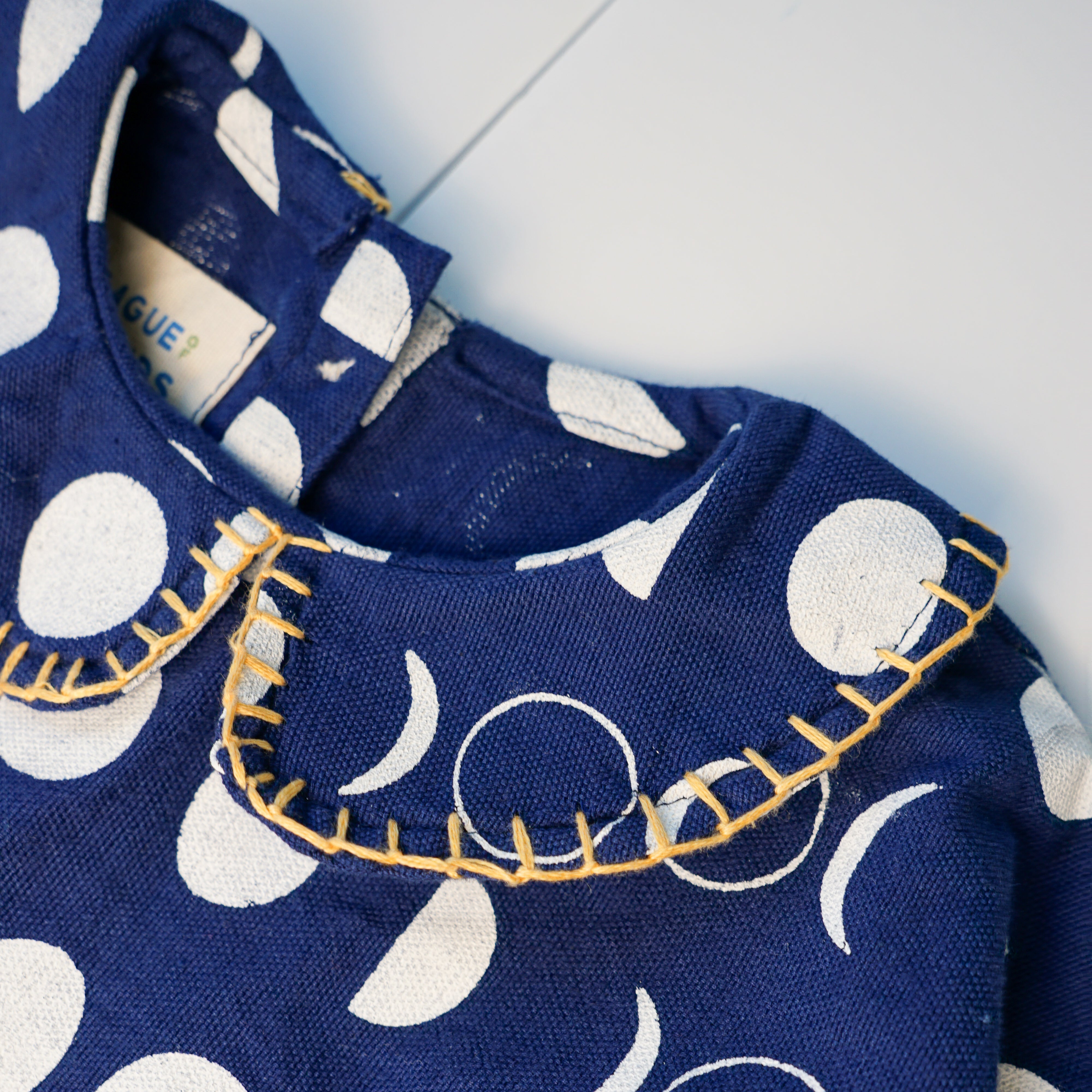 Navy Moon Phases tiered dress with cream moon print, puff sleeves and yellow stitching on the Peter Pan collar and hem.
