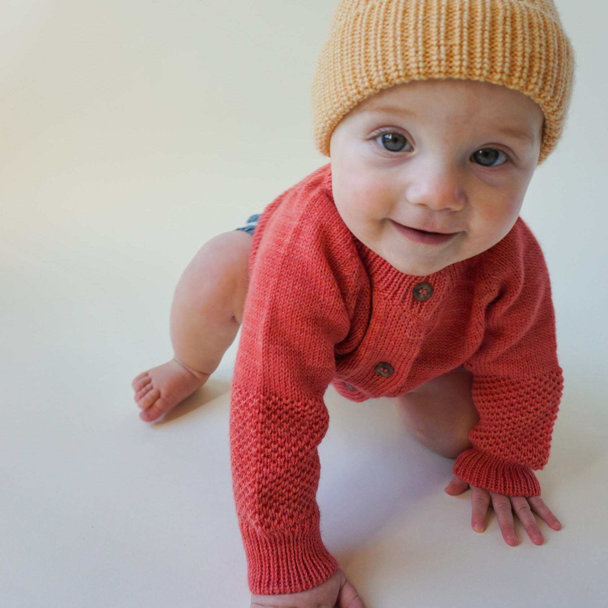 Toddler playing in red 2-Texture Raglan Sleeve Cardigan and yellow beanie knit hat