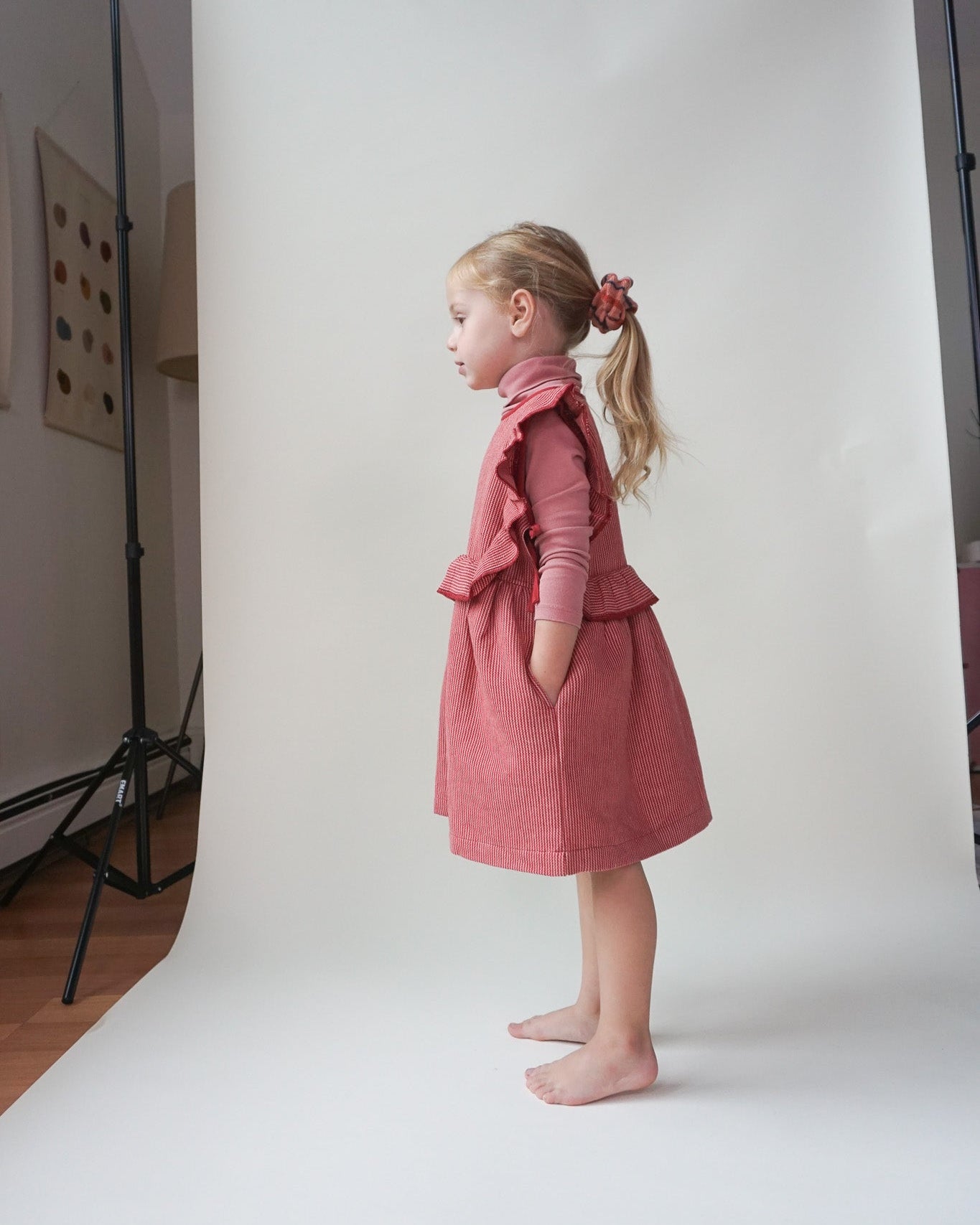 Young girl in a pink dress standing against a white backdrop