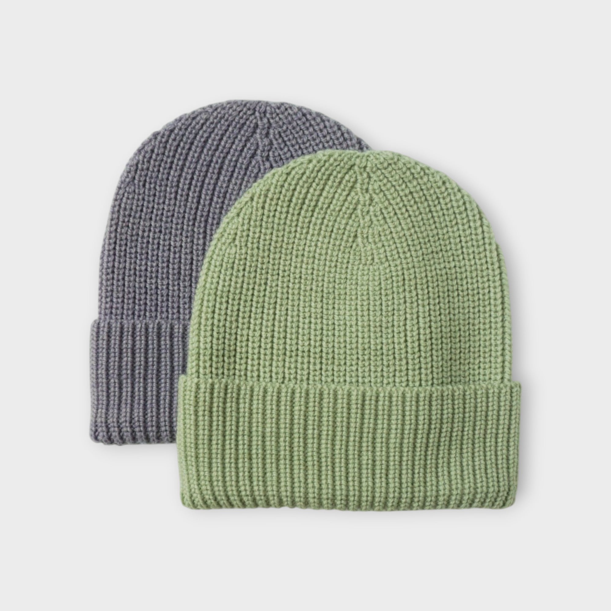 Two knit beanie hats, one light purple and one green, on a light gray background.