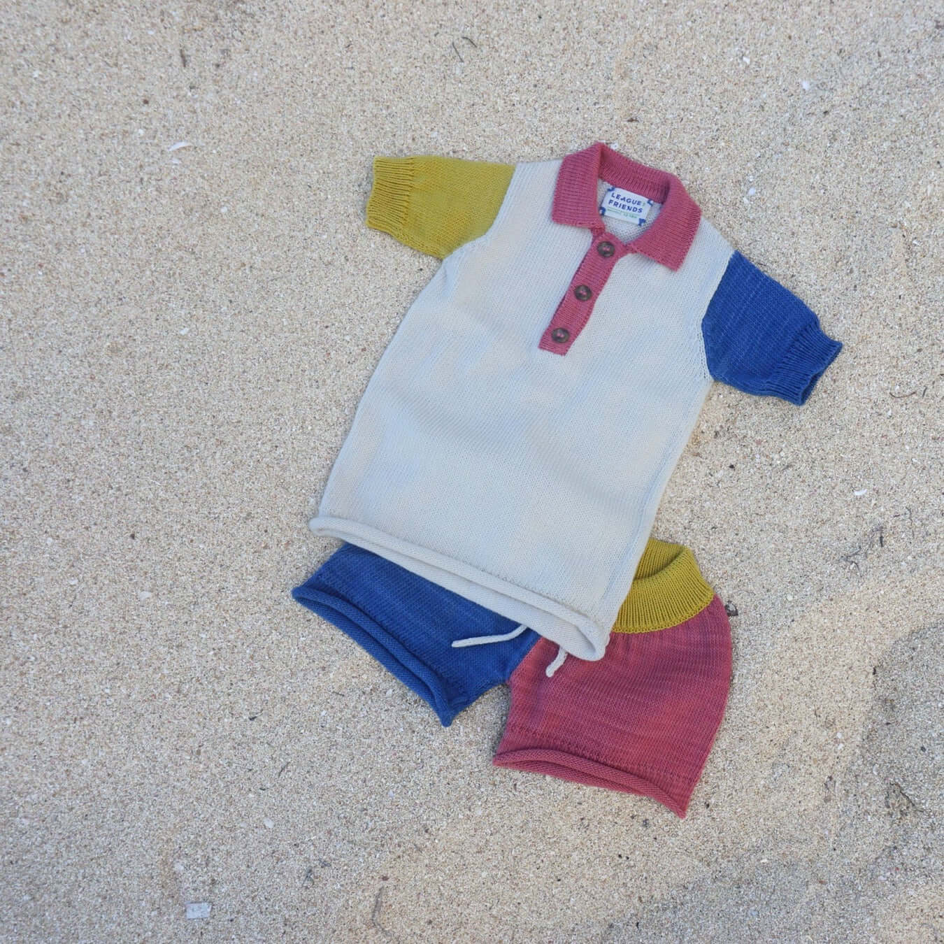 primary colorblocked polo tee and short laying on sand