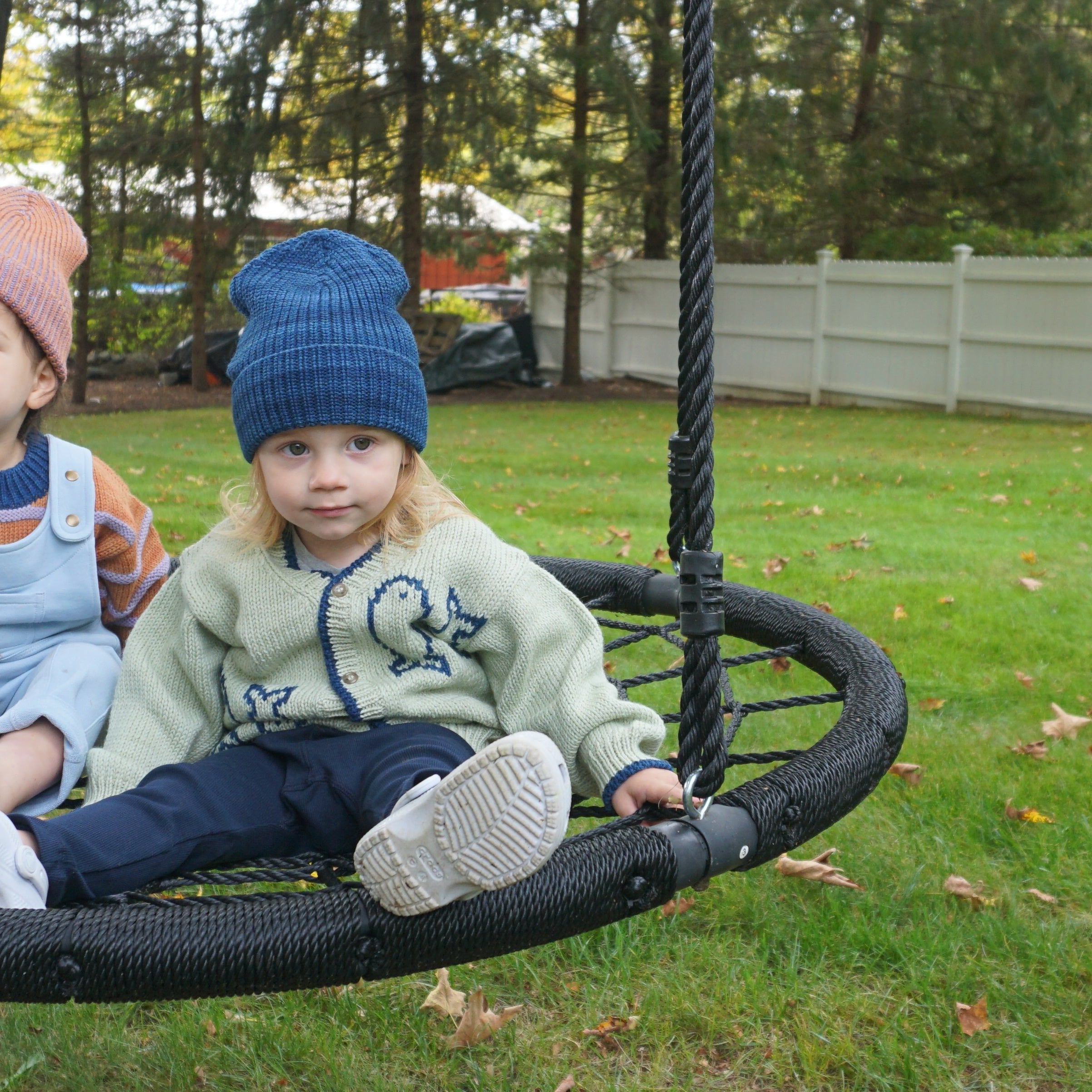 toddlers wearing beanie hats on swing