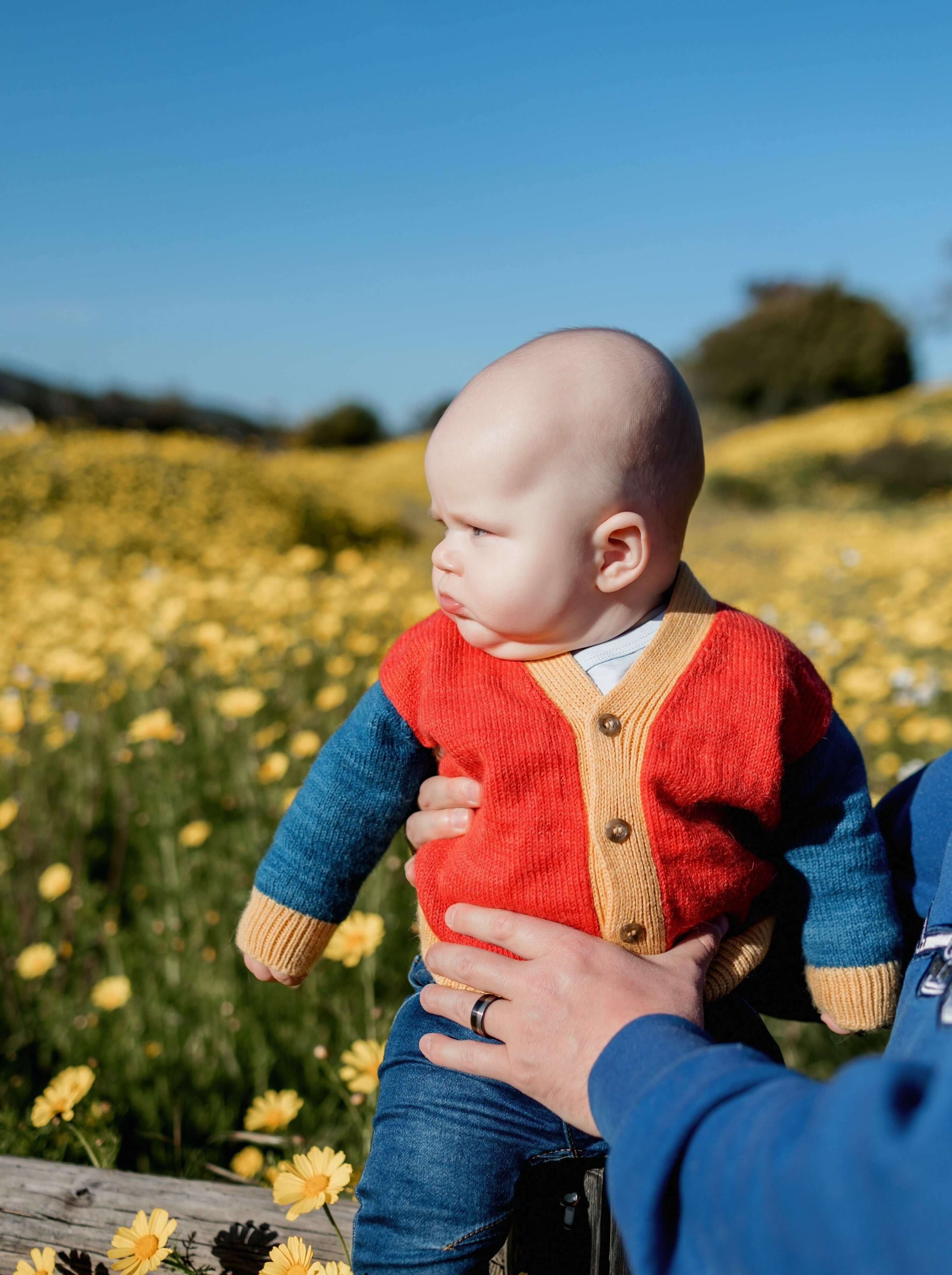 Baby sitting in flower field wearing primary colored Colorblocked V-Neck Cardigan