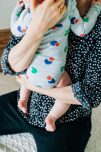 mom holding baby wearing colorful bodysuit showing backside of baby