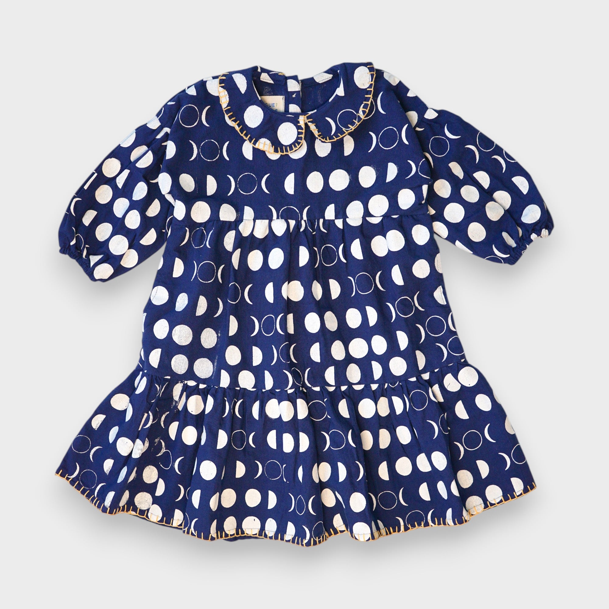 Navy Moon Phases tiered dress with cream moon print, puff sleeves and yellow stitching on the Peter Pan collar and hem.