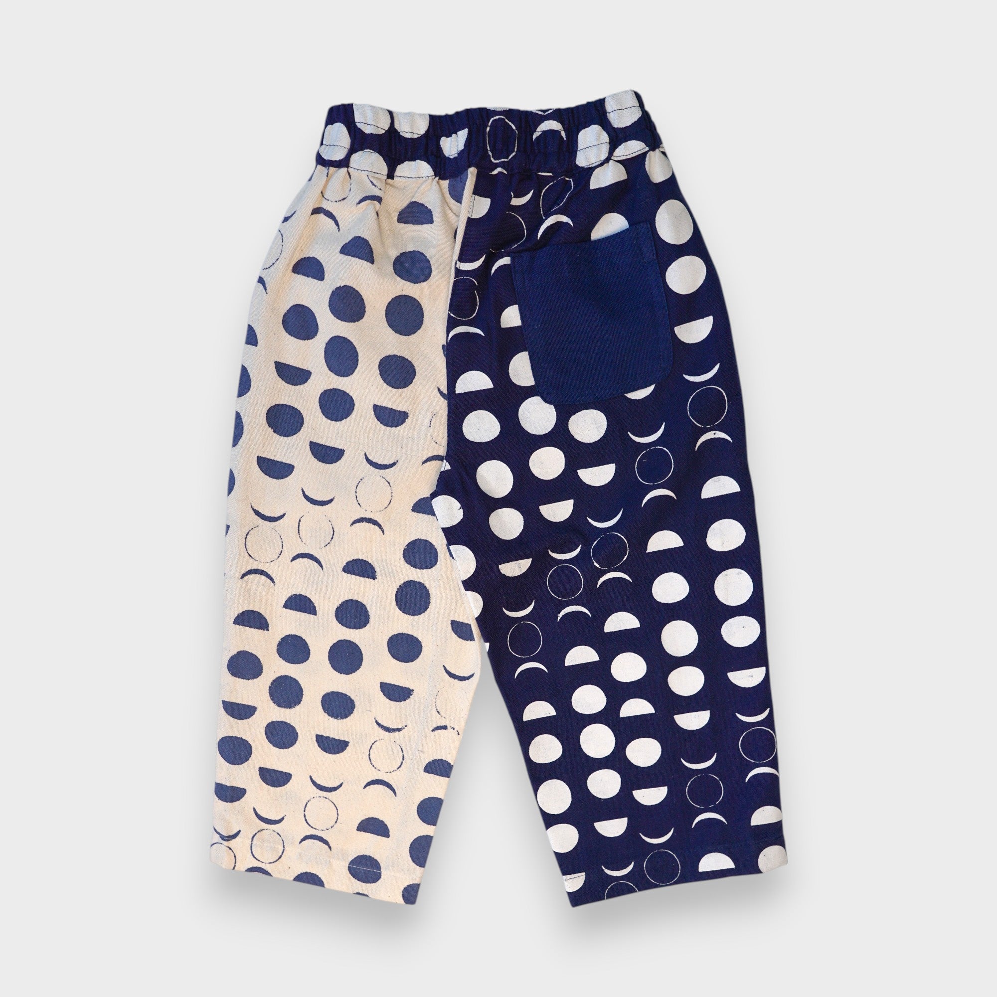 Front of navy and cream Moon Phases pants with contrasting moon-print legs, elastic waistband and large navy patch pockets.