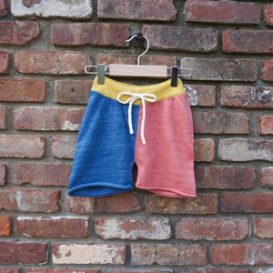 colorblock knit shorts hanging on a brick wall