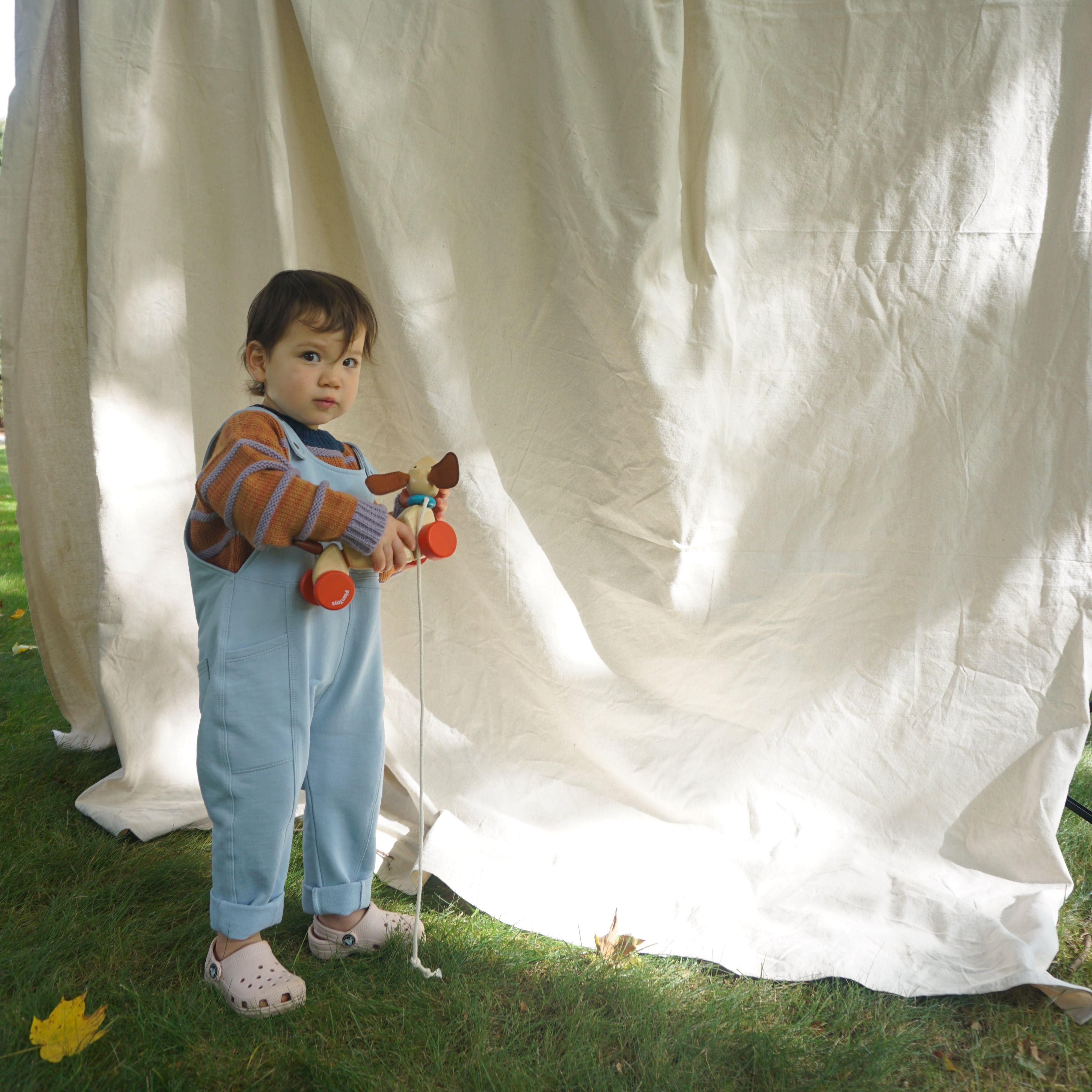 toddler wearing cotton overalls and striped wool alpaca sweater