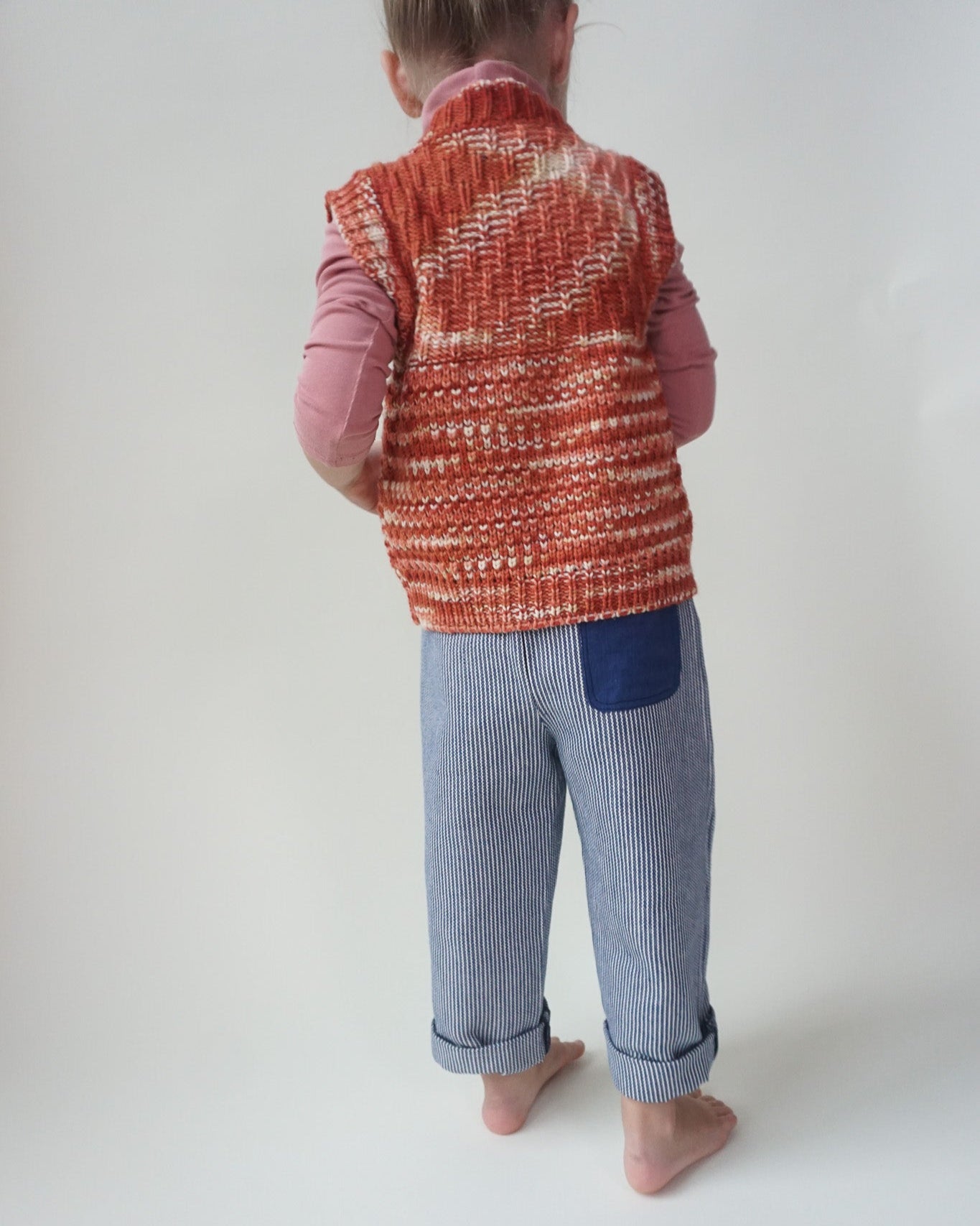 Child wearing a red and white patterned vest on a plain background