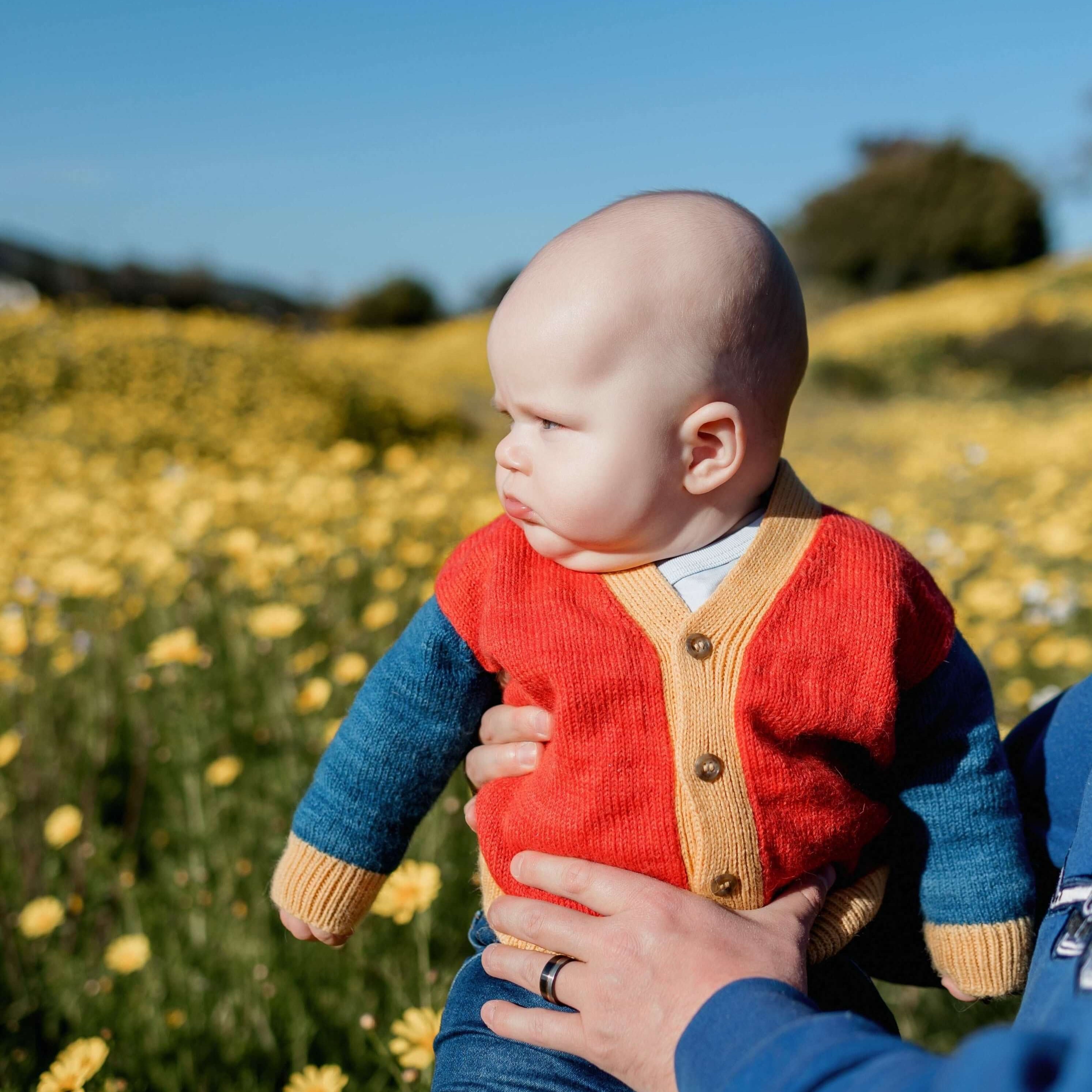 Baby sitting in flower field wearing primary colored Colorblocked V-Neck Cardigan