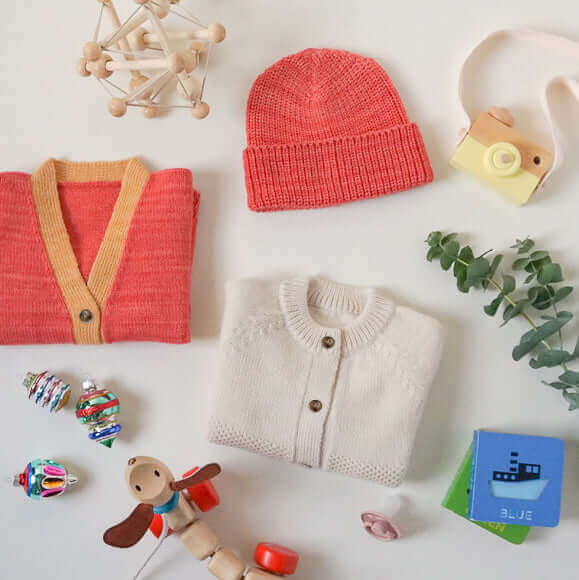 baby sweaters, beanie hats and toys on a white background with christmas ornaments
